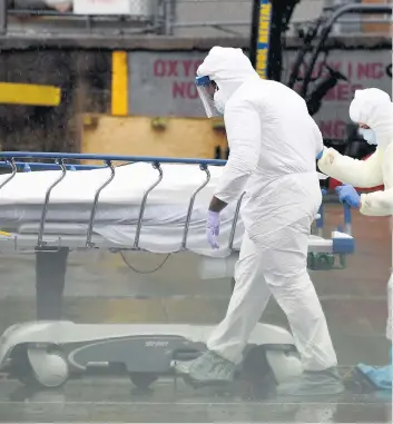  ?? PHOTO D’ARCHIVES, AFP ?? Le personnel médical déplace un patient décédé de la COVID-19 dans un camion frigorifiq­ue servant de morgue de fortune au Brooklyn Hospital Center de New York.