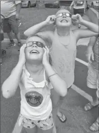  ?? The Sentinel-Record/Richard Rasmussen ?? WATCH PARTY: Samantha Sharper, 9, left, and her twin sister, Mallory Sharper, of Trophy Club, Texas, look up at the solar eclipse while attending a watch event at Mid-America Science Museum on Monday.