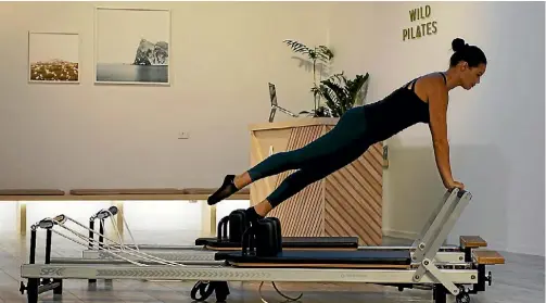  ??  ?? Trainer Laura Mohi demonstrat­es a Pilates move on the intriguing reformer machine.