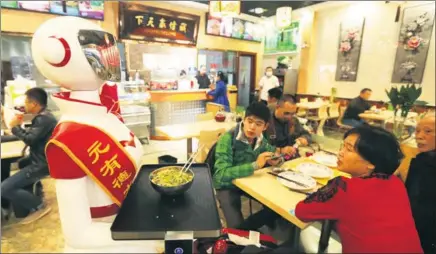  ?? ZHANG XIUKE / FOR CHINA DAILY ?? A robotic waiter delivers a bowl of noodles to customers at a restaurant in Urumqi, Xinjiang Uygur autonomous region.