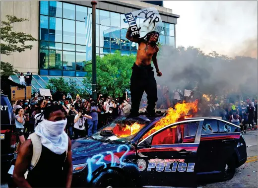  ??  ?? FURY: A man stands on top of a burning police car during a protest in Atlanta, Georgia – one of many held in the wake of George Floyd’s death