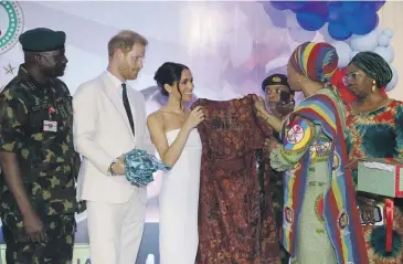  ?? GETTY IMAGES ?? Prince Harry and Meghan, Duchess of Sussex, receive gifts of Nigerian fashion during a visit to charity organisati­on Nigeria Unconquere­d in Abuja. Surfing a demographi­c wave that is predicted to make it the third-most populous nation by 2050, Nigeria has turned itself into a cultural powerhouse in the past decade.