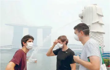  ?? — Reuters ?? Tourists wearing masks visit the Merlion Park shrouded by haze in Singapore yesterday. The 3-hour Pollutant Standards Index (PSI) reached a high of 262 at 12 noon (0400 GMT) on Thursday.