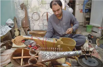  ?? — AFP ?? A Pakistani craftsman makes a rubab, a traditiona­l instrument used in Pashto music at a workshop in Peshawar.