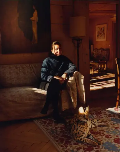  ??  ?? HARUMI KLOSSOWSKA DE ROLA avec son serval Nelson Mandela. Elle est assise dans un canapé hérité de l’époque ancienne où le chalet était un hôtel.