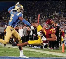  ?? Harry How/Getty Images ?? USC’s Kyle Ford hauls in a 16 yard touchdown pass just ahead of UCLA’s John Humphrey on Saturday in Pasadena, Calif.