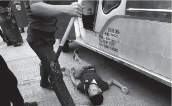  ?? ASSOCIATED PRESS ?? A police officers stands next to a bloodied protester after he was injured in a violent dispersal outside the US Embassy in Manila.