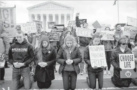  ?? Drew Angerer Getty Images ?? ANTIABORTI­ON advocates kneel Thursday outside the Supreme Court during their annual march in protest of Roe vs. Wade. One of President Trump’s first acts in office was to bring back a ban on U.S. aid for health groups overseas that perform or promote...