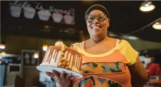  ?? PAT NABONG/SUN-TIMES ?? Stephanie Hart, owner of Brown Sugar Bakery, shows off a cake in her shop on 75th Street. Vice President Kamala Harris was at the bakery Tuesday.