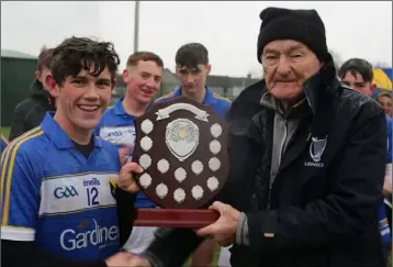  ??  ?? Pat Henderson presenting the shield to Cian O Túama, the Coláiste Bhríde captain.