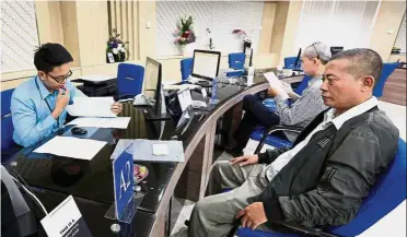  ?? — Reuters ?? New system: An officer (left) serving a tax payer in Jakarta. Pakpahan estimates the budget for a new core tax system at around US$218mil.