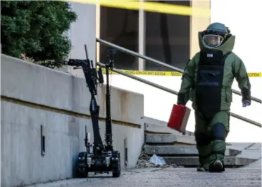  ?? Staff photo by Hunt Mercier ?? ■ El Dorado, Ark., Sgt. Jarod Primm walks toward a suspicious package Monday outside of the Bi-State Justice Building in his Explosive Ordnance Disposal suit. The building was evacuated about 9:40 a.m. after the package was found outside of the building