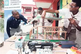  ?? CONTRIBUTE­D ?? The Petroleum Corporatio­n of Jamaica’s (PCJ) manager, renewable energy and energy efficiency, Dr Peter Ruddock (left), examines the solar photovolta­ic (PV) panels on the roof of the model designed by a team of students from the Herbert Morrison...