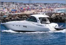  ?? WAYNE PARRY - THE ASSOCIATED PRESS ?? A yacht cruises through the Manasquan Inlet as a large crowd fills the beach in Manasquan, N.J. on June 28. With large crowds expected at the Jersey Shore for the July Fourth weekend, some are worried that a failure to heed mask-wearing and social distancing protocols could accelerate the spread of the coronaviru­s.