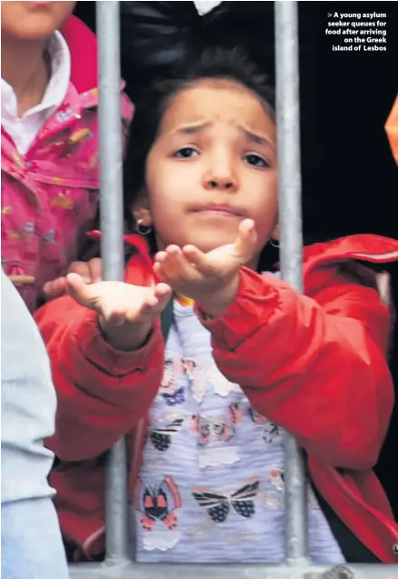  ??  ?? > A young asylum seeker queues for food after arriving on the Greek island of Lesbos