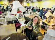  ?? POSTMEDIA NEWS ?? Jo-Anne Lauzer checks out an old lamp at a thrift sale in Vancouver.