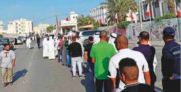  ?? AFP ?? Bahrainis queue outside a polling station in the capital Manama yesterday to cast their votes in the parliament­ary election. The polls opened at 8am local time.