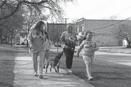  ?? PHOTOS BY ANDY DOSSETT / DEMOCRAT AND CHRONICLE ?? (Left to right) Deanna Viera, Elissa Lopez and Elicia Lopez accompany Luna, a prospectiv­e foster dog, on a walk as Rochester Animal Services volunteer Ann Marie Switzer hands the brown-haired, mixed breed treats last week.