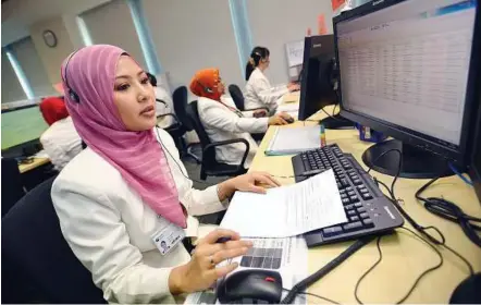  ?? — The Straits Times / Asia News Network ?? Follow-up service: Iriany Kadarsy Ramlee, 26, nurse telecarer from Eastern Health Alliance’s health management unit communicat­ing with a patient over the phone.