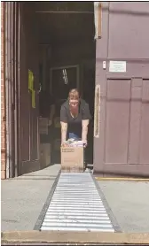  ??  ?? Social distancing at it’s best – Deann Little slides a hamper out the side door loading ramp at the Moose Jaw and District Food Bank