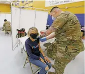  ?? LUIS SÁNCHEZ SATURNO/THE NEW MEXICAN ?? Catherine Trapani of Santa Fe receives a vaccine Tuesday from Sgt. Ivan Gomez of the New Mexico National Guard at the New Mexico Department of Health’s COVID-19 vaccine distributi­on center in the Santa Fe High School gymnasium. The state will soon identify in its invitation­s which vaccine will be administer­ed, based on availabili­ty.