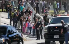  ?? GINA FERAZZI/LOS ANGELES TIMES ?? Left: San Bernardino police officers help evacuate children to waiting school buses after a shooting inside North Park Elementary School on Monday in San Bernardino.