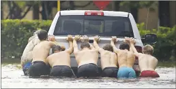  ?? CHARLIE RIEDEL — ASSOCIATED PRESS ?? Men push a stalled pickup truck through a flooded street in Houston, after Tropical Storm Harvey deluged the area on Sunday.