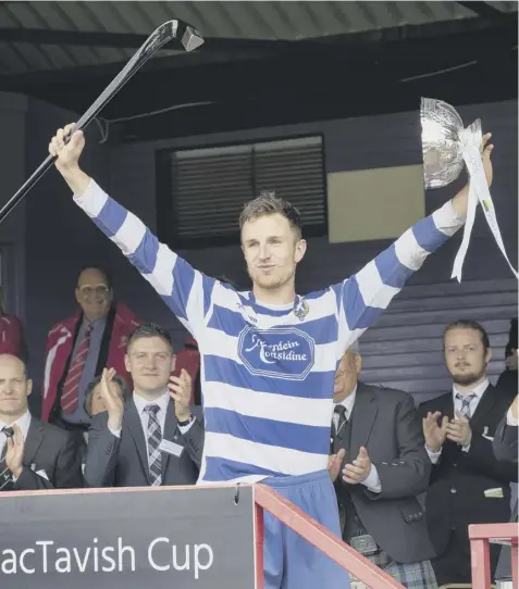  ??  ?? 0 Newtonmore captain Andy Mackintosh lifts the Rose Bowl trophy after their third Mactavish Cup win in a row.