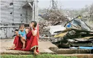  ?? (Photo by Dibyangshu SARKAR / AFP) ?? An Indian woman sits with her child next to storm-damaged buildings in Puri in the eastern Indian state of Odisha on May 4, after Cyclone Fani swept through the area.
