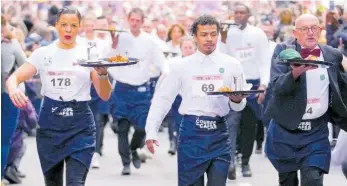  ?? AP ?? Waiters carry trays with a cup of coffee, a croissant and a glass of water as they take part in a waiters’ run through the streets of Paris, France, on Sunday. AP