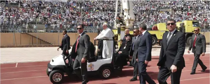  ??  ?? CAIRO: Pope Francis is surrounded by security as he rides an uncovered Popemobile before the start of a mass yesterday at a stadium in Cairo. — AFP