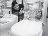  ?? WANG JIANKANG / FOR CHINA DAILY ?? A woman inspects a new toilet design at the 2013 China Energy Saving Exhibition in Suzhou, Jiangsu province, on June 8. The toilet is designed to use less water.