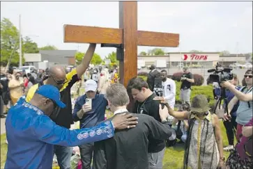  ?? Joshua Bessex Associated Press ?? A GROUP prays at a memorial for the victims of the Buffalo shooting. Ten people were killed and three hurt.