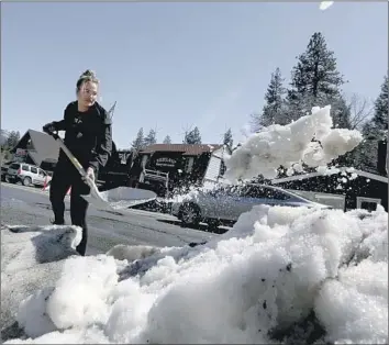  ?? BONNIE SUNSERI Luis Sinco Los Angeles Times ?? shovels snow at a parking lot on Lake Street in Crestline. Potential triggers for rapid snowmelt could be an early season heat wave or another series of warm storms, a UCLA climate scientist says.