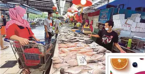  ?? ?? JAMAL (kanan) membantu pelanggan memilih ikan yang dijual di gerainya di Pandan, Johor Bahru, semalam.- Gambar NSTP/NUR AISYAH MAZALAN