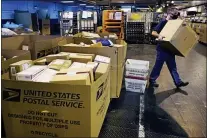  ?? CHARLES KRUPA - THE ASSOCIATED PRESS ?? A worker carries a large parcel at the United States Postal Service sorting and processing facility, Nov. 18, in Boston. Last year’s holiday season was far from the most wonderful time of the year for the beleaguere­d U.S. Postal Service.
Shippers are now gearing up for another holiday crush.