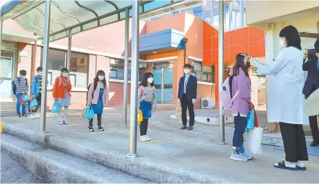  ?? Yonhap ?? Students have their temperatur­es checked at an elementary school in Muan, South Jeolla Province, May 20.