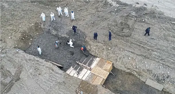  ??  ?? EMERGENCY MEASURES: Drone footage, later confiscate­d by police, captured workers stacking wooden coffins in deep trenches on New York’s Hart Island