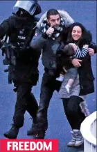  ??  ?? The ecstatic mother, her child and her partner finally walk free from the siege, escorted by a riot officer
