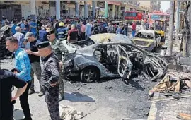  ?? Karim Kadim Associated Press ?? IRAQI security forces and civilians inspect the site of a deadly bombing in Baghdad on May 30. Another bomb exploded outside an ice cream shop the same day.