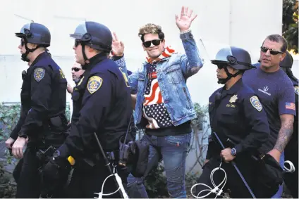  ?? Scott Strazzante / The Chronicle ?? Milo Yiannopoul­os leaves Sproul Plaza after a brief UC Berkeley appearance that sparked protests on campus.