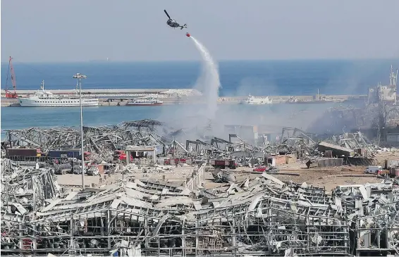  ??  ?? An army helicopter drops water on Wednesday at the scene of a massive explosion that tore through the seaport of Beirut, Lebanon, a day earlier.