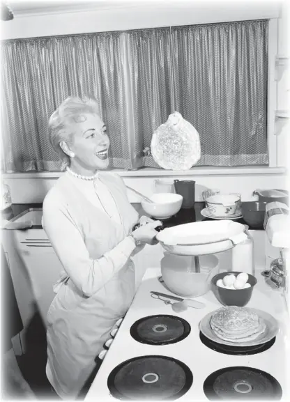  ?? HENRY TREGILLAS/ VANCOUVER SUN FILES ?? Vancouver Sun editor Marie Moreau makes pancakes — with a suspicious­ly airborne fl apjack — in this photo from Oct. 11, 1957.