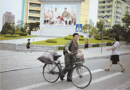  ?? AP PHOTOS ?? ENCOURAGIN­G SIGN: A mural of past North Korean leaders Kim Il Sung and Kim Jong Il, above, towers over a street in Pyongyang yesterday. President Trump, below, exits Air Force One after returning from the summit.