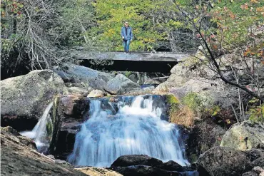  ?? [AP PHOTOS] ?? EAST MONTPELIER, VT. A hiker walks out on a bridge to view a waterfall at the Crystal Cascades on Sept. 28 in Pinkham Notch, N.H.