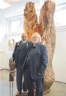  ?? FOTO: BABETTE CAESAR ?? Peter Gebhard (rechts) vor seiner jahrhunder­tealten Ulme und Carlo Schuchmann (links) mit einer seiner Figuren.