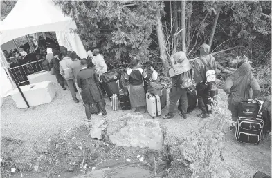  ?? GEOFF ROBINS / AFP / GETTY IMAGES ?? A long line of asylum seekers wait to illegally cross the Canada-u.s. border near Champlain, N.Y., last August. In June, the Immigratio­n department recorded just 1,263 “RCMP intercepti­ons” — less than half what it was in April.