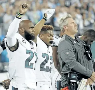  ?? MIKE MCCARN/THE ASSOCIATED PRESS ?? Philadelph­ia Eagles players Malcolm Jenkins (27) and Rodney McLeod (23) raise their fists as they stand with head coach Doug Pederson during the national anthem before Thursday’s game against the Carolina Panthers in Charlotte, N.C.