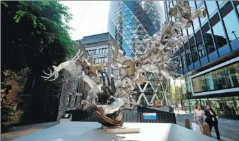  ?? PROVIDED TO CHINA DAILY ?? Pedestrian­s walk past a sculpture in London’s Square Mile financial district. London is the world leader in offshore renminbi foreign exchange trading.