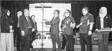  ??  ?? Dr Annuar (fourth right) cuts the ribbon to reveal a banner when opening the colloquium , witnessed by Siman (third right), Nordin (second left) and Twin (second right).